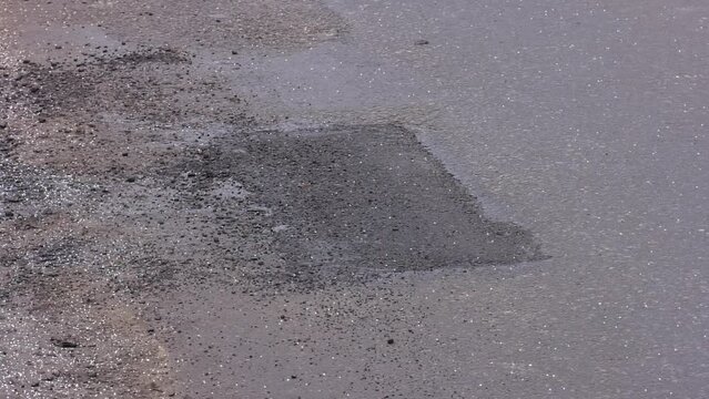 asphalt tarmac patch on concrete ground repair pavement road in parking lot. Asphalt road repair of poor quality. Pothole asphalt road repairs. A newly patched roadway in a bad condition. 