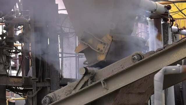 Asphalt being transported by a large cargo container at an asphalt and cement factory. Conveyor belt in a factory of building materials production. 
