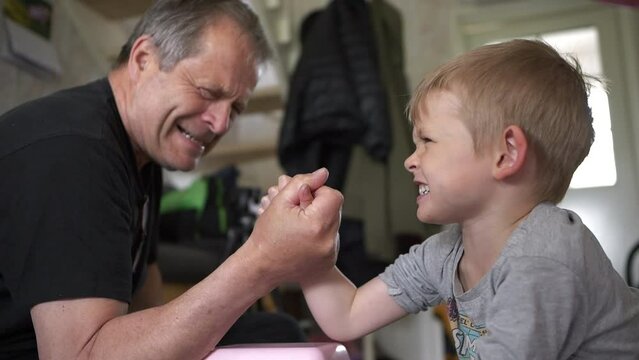 Slow motion shot of Grandfather and Grandson arm wrestling with Authentic facial expressions