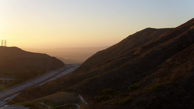 Aerial Panning Shot Of Cars Moving On Roads Amidst Mountains Against Clear Sky During Sunset - Camarillo, California