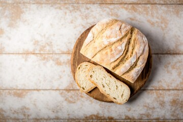 freshly baked bread sliced into slices, freshly baked bread on top of circular wooden board on a black stone wooden table