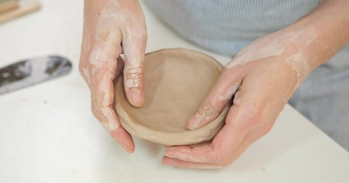 woman forming clay pot shape by hands, closeup in artistic studio