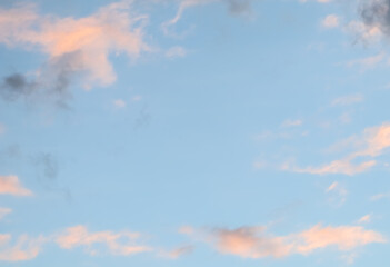 Blue sky background with pale pink clouds at sunset