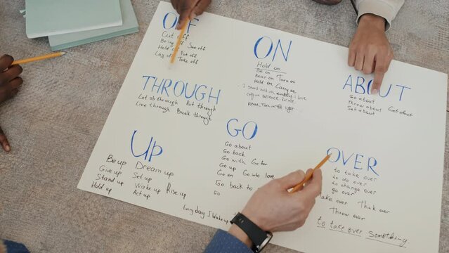 From above view of unrecognizable ethnically diverse students learning English phrasal verbs