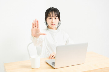 PCを使いながらNGのサインをする女性