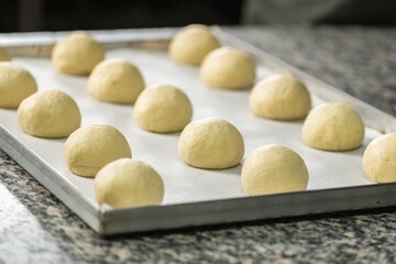 Fototapeta na wymiar Balls of Dough Placed On a Cooking Paper in a Baking Pan