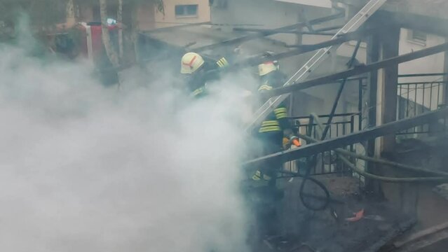 Firemen in action on burning ruins of building