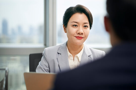 young asian business woman conversing with colleague businessman in modern office