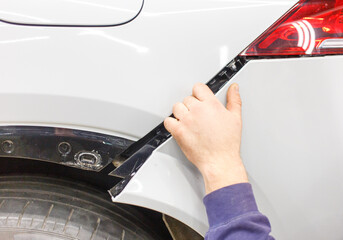 The master mechanic installs the bumper on the car. An auto mechanic repairs the car body by...