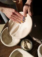 The baker holds a basket for the bread and sprinkles with flour
