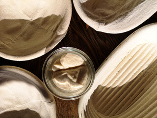 Dough baskets and a glass of sourdough on the table, top view