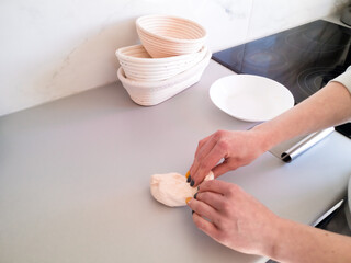 Obraz na płótnie Canvas Woman kneads dough in the kitchen against the kitchen utensils