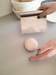Hands of women form a bun of raw dough for baking bread