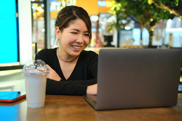 Asian woman sitting at a table in a restaurant and working with 