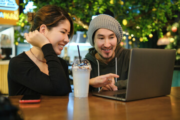 Asian couple sitting at a table in a restaurant and working with