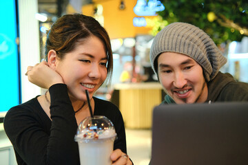 Asian couple sitting at a table in a restaurant and working with