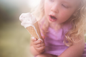 toddler girl holding melting ice cream cone