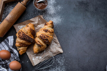 Delicious freshly baked croissants with chocolate on a dark background. French breakfast. Delicious pastries close-up. The context of a bakery with delicious bread. Confectionery products.