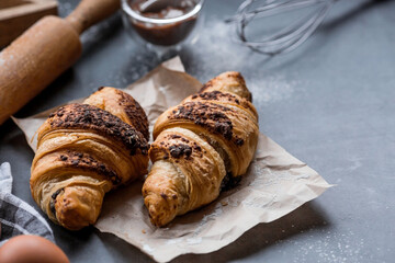 Delicious freshly baked croissants with chocolate on a dark background. French breakfast. Delicious pastries close-up. The context of a bakery with delicious bread. Confectionery products.