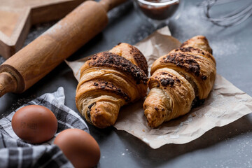 Delicious freshly baked croissants with chocolate on a dark background. French breakfast. Delicious pastries close-up. The context of a bakery with delicious bread. Confectionery products.