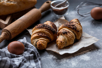 Delicious freshly baked croissants with chocolate on a dark background. French breakfast. Delicious pastries close-up. The context of a bakery with delicious bread. Confectionery products.