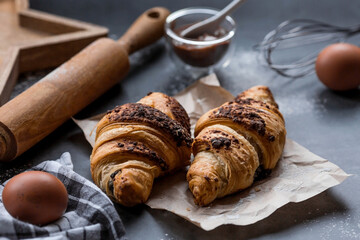 Delicious freshly baked croissants with chocolate on a dark background. French breakfast. Delicious pastries close-up. The context of a bakery with delicious bread. Confectionery products.