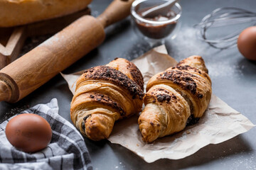 Delicious freshly baked croissants with chocolate on a dark background. French breakfast. Delicious pastries close-up. The context of a bakery with delicious bread. Confectionery products.