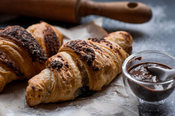 Delicious freshly baked croissants with chocolate on a dark background. French breakfast. Delicious pastries close-up. The context of a bakery with delicious bread. Confectionery products.