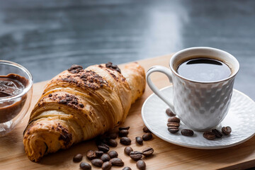 Delicious freshly baked croissants with chocolate and coffee on a dark background. French breakfast. Delicious pastries close-up. The context of a bakery with delicious bread. Confectionery products.