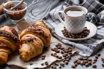 Delicious freshly baked croissants with chocolate and coffee on a dark background. French breakfast. Delicious pastries close-up. The context of a bakery with delicious bread. Confectionery products.