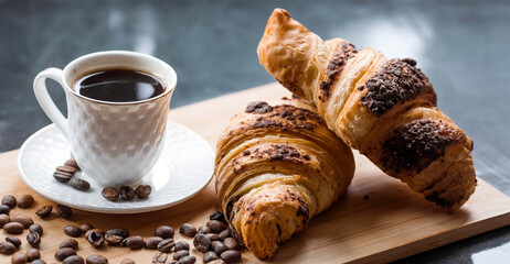 Delicious freshly baked croissants with chocolate and coffee on a dark background. French breakfast. Delicious pastries close-up. The context of a bakery with delicious bread. Confectionery products.