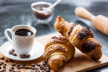 Delicious freshly baked croissants with chocolate and coffee on a dark background. French breakfast. Delicious pastries close-up. The context of a bakery with delicious bread. Confectionery products.