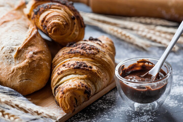 Delicious freshly baked croissants with chocolate on a dark background. French breakfast. Delicious pastries close-up. The context of a bakery with delicious bread. Confectionery products.
