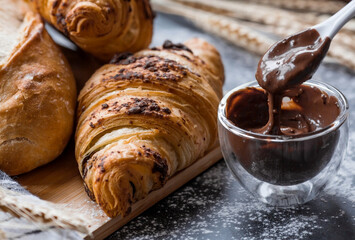 Delicious freshly baked croissants with chocolate on a dark background. French breakfast. Delicious pastries close-up. The context of a bakery with delicious bread. Confectionery products.