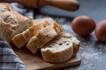 Fresh delicious bread, wooden rolling pin, eggs and flour close-up. Freshly baked bread baguette with a golden crust. The context of a bakery with delicious bread. Confectionery products.