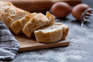 Fresh delicious bread, wooden rolling pin, eggs and flour close-up. Freshly baked bread baguette with a golden crust. The context of a bakery with delicious bread. Confectionery products.