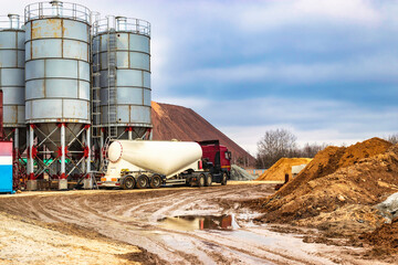 Large truck for transporting cement. A cement truck unloads cement at a concrete plant. Concrete...
