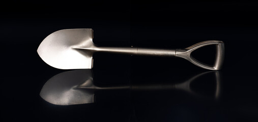 golden business shovel isolated on black background © serikbaib