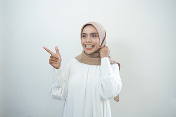 Naklejka premium Cheerful beautiful Asian woman in white dress pointing fingers aside at copy space isolated over white background