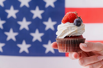 hand holding sweet cupcake with blueberries and strawberry , flag background