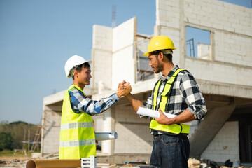 Contractor and architect looking at plan, tablet, laptop and talking about working on big project. Building in construction process interior.