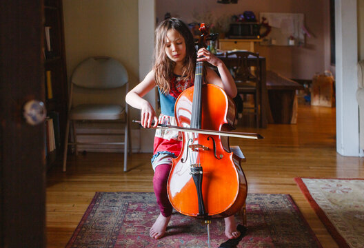 A young barefoot girl plays cello passionately with eyes closed