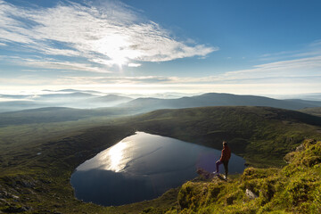 man looking from mountain top to heart shaped lake