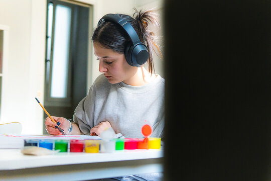 pretty young girl painting a canvas at home