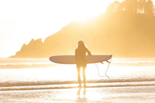 backlit surfer heading out into the water in Oregon