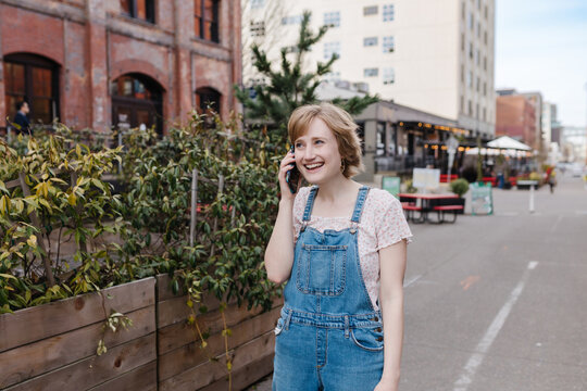 Laughing young woman talking on cell phone downtown