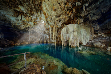 Obraz na płótnie Canvas Cenote Dzitnup Xkeken, cave south of Valladolid. Landscape in Yucatán, Mexico. Green blue water lake in cave, light in the hole. Travel in Mexico.