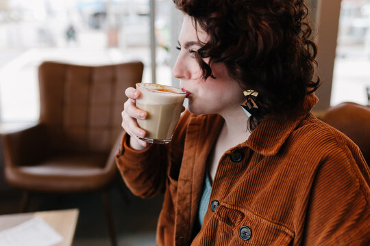 Profile view of beautiful woman taking sip of latte