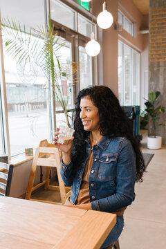 Happy Latina woman smiling holding coffee in cafe