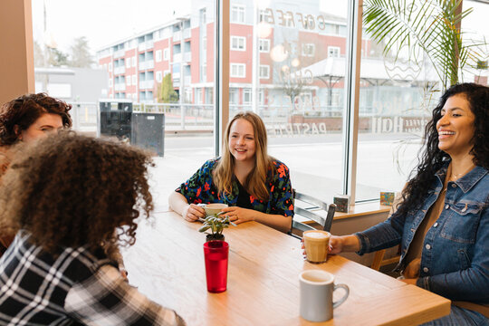 Diverse friend group laughing inside coffee shop